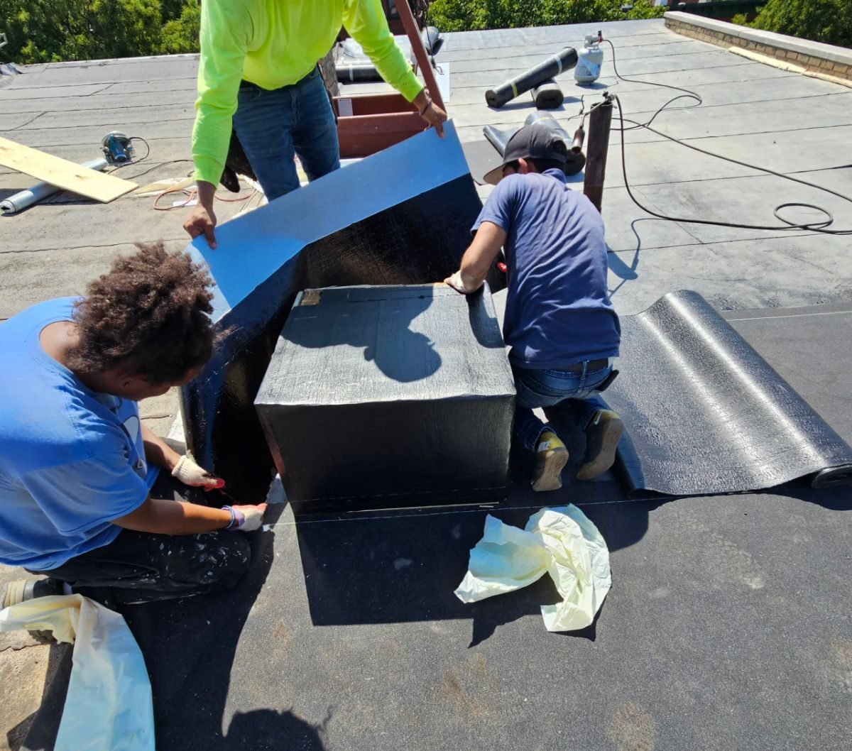 Roofing contractors sealing flat roof vent with waterproof membrane in NYC
