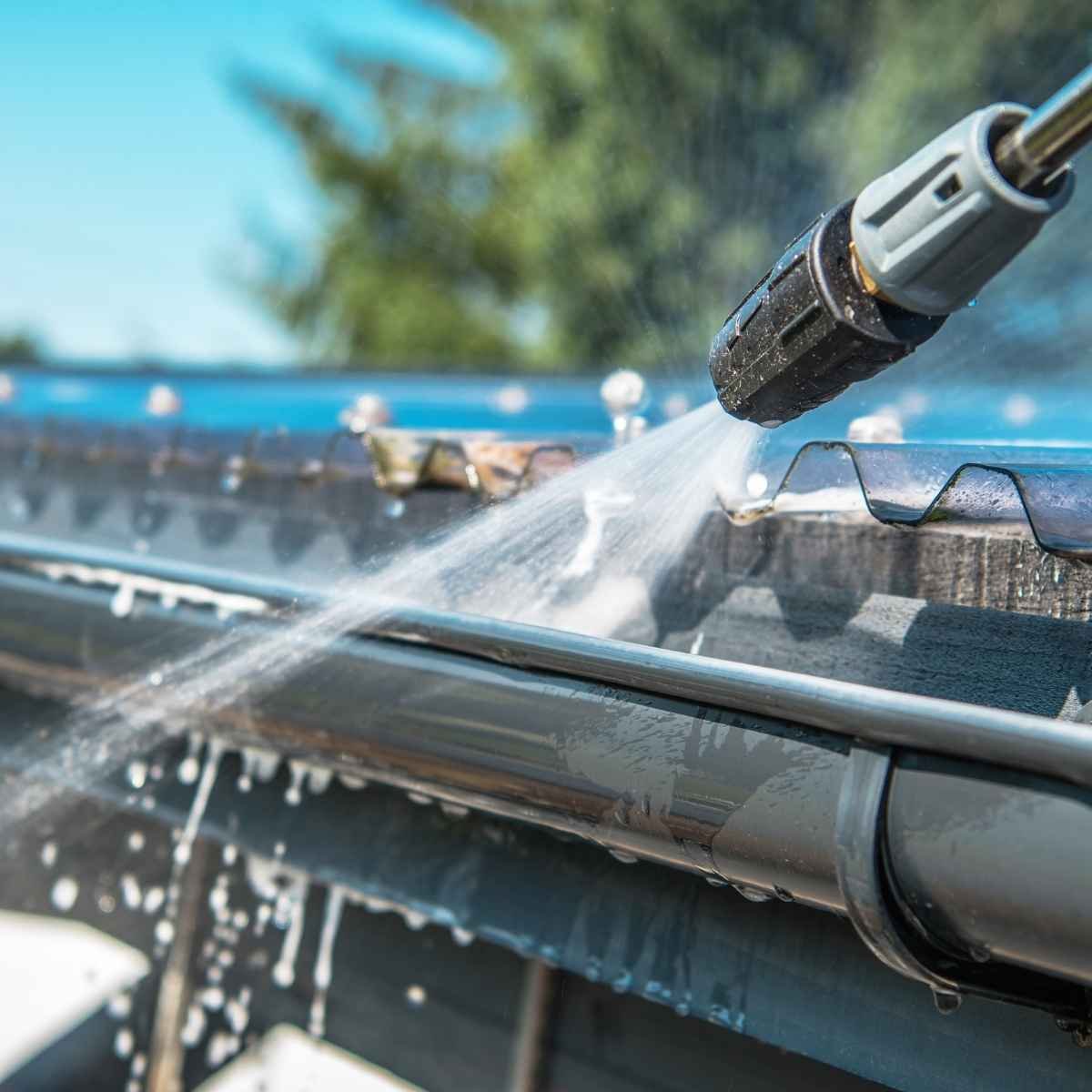 Close-up of professional gutter cleaning with high-pressure water jet removing dirt and debris.
