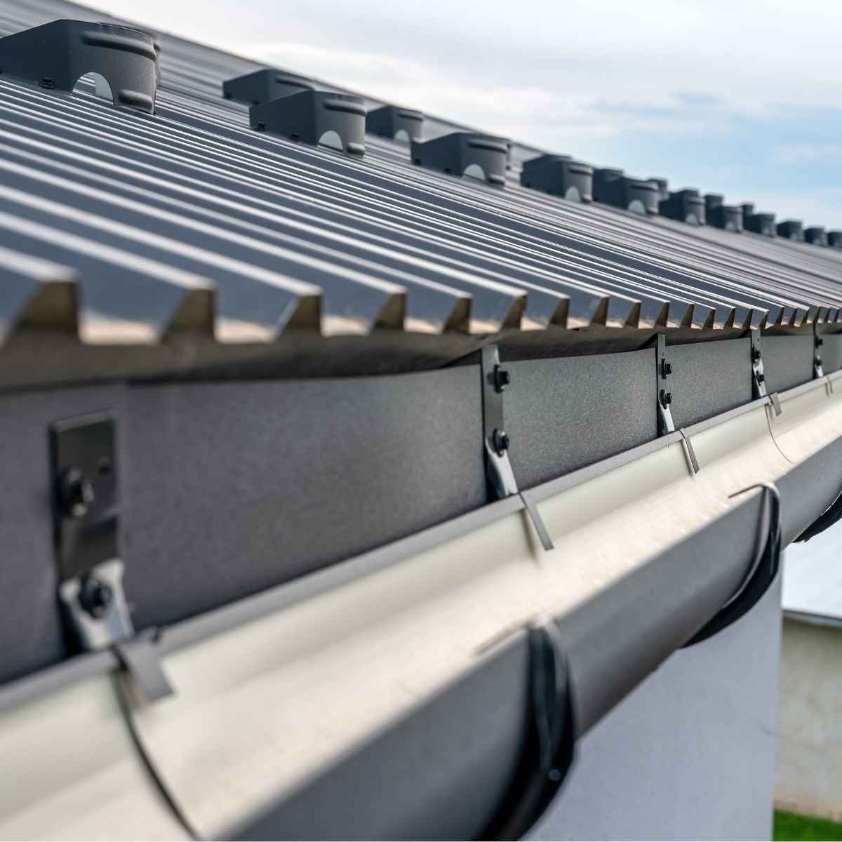 Close-up view of newly installed gutter system on a modern metal roof for effective rainwater management.