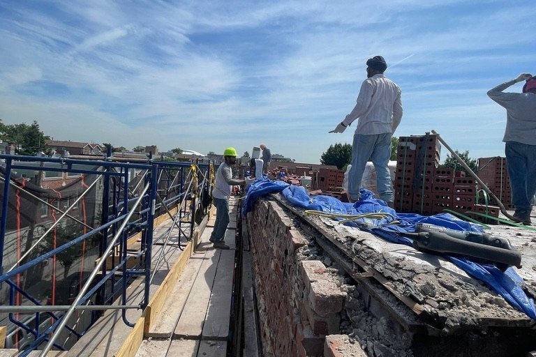Masons rebuilding a rooftop parapet wall on a NYC building